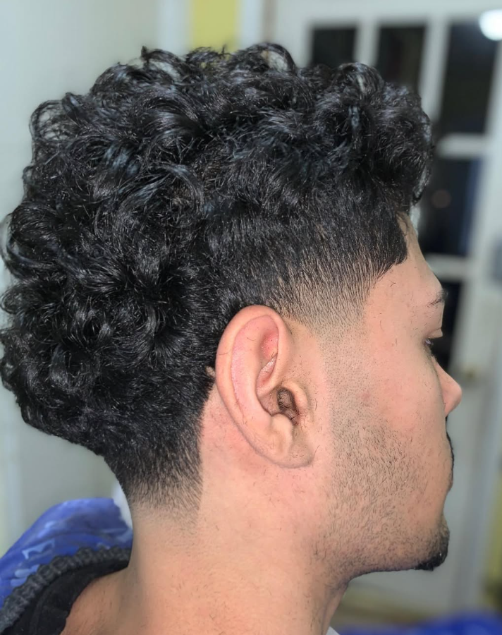 Side profile of a client with defined curls on top and a smooth low taper fade